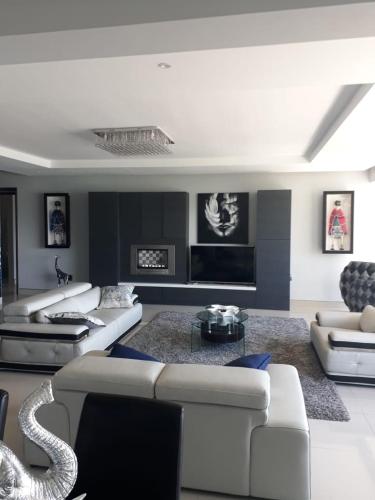 a living room with white couches and a fireplace at GORDON's SHORE LUXURY APARTMENTS - Solar Powered in Gordonʼs Bay