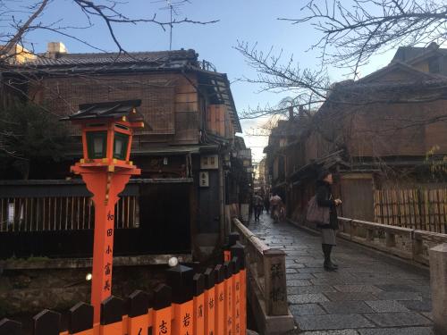 a woman walking down a street with a light on a pole at Kyoto Gion U-BELL Hotel in Kyoto
