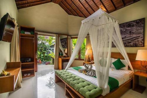 a bedroom with a bed with a canopy at Bakung Ubud Resort and Villa in Ubud