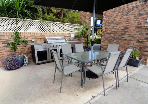 a glass table and chairs with an outdoor kitchen at Sandhurst Motor Inn Bendigo in Bendigo