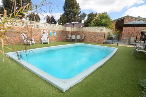 a large swimming pool in a yard with grass at Sandhurst Motor Inn Bendigo in Bendigo