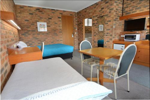 a room with a bed and a table and a bed and a kitchen at Sandhurst Motor Inn Bendigo in Bendigo
