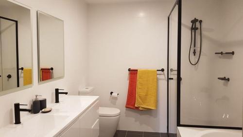 a white bathroom with a toilet and a shower at Beachfront Boogaloo in Huskisson