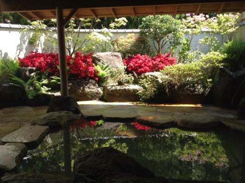 a garden with red flowers and a pond at Mount View Hakone in Hakone