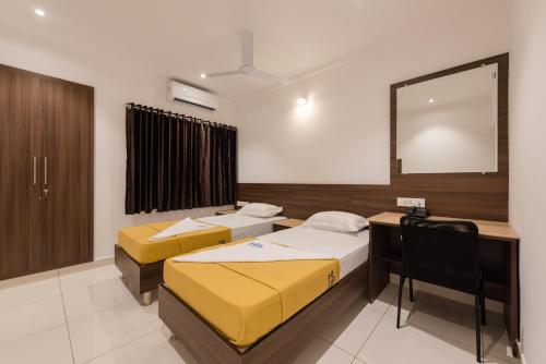 a room with two beds and a desk and a mirror at Hotel Karuna Residency in Mangalore