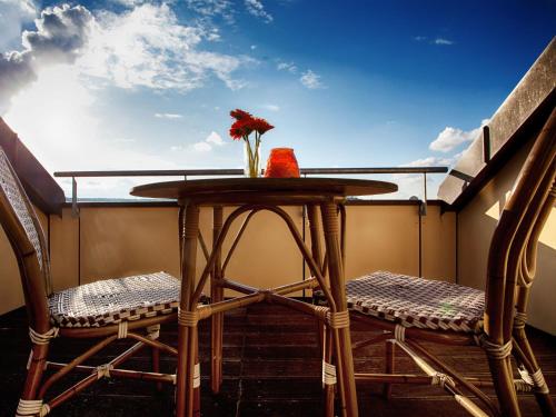 einen Tisch mit 2 Stühlen und eine Vase Blumen auf dem Balkon in der Unterkunft Hostel Alex 30 in Stuttgart