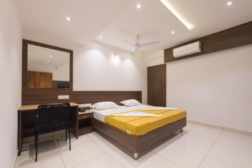 a bedroom with a bed and a desk and a mirror at Hotel Karuna Residency in Mangalore