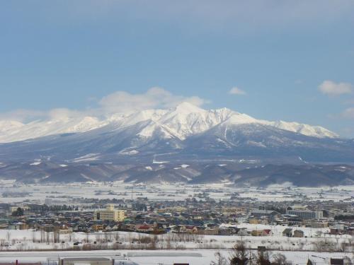 a view of a city with snow covered mountains at Chalet Fuyuri in Furano