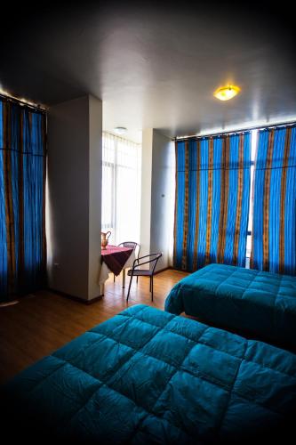a bedroom with two beds and a chair and windows at Yacht Lago Titicaca in Ichu