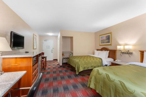 a hotel room with two beds and a flat screen tv at Quality Inn & Suites Oceanside Near Camp Pendleton in Oceanside