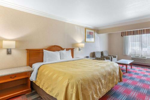 a hotel room with a large bed and a chair at Quality Inn & Suites Oceanside Near Camp Pendleton in Oceanside