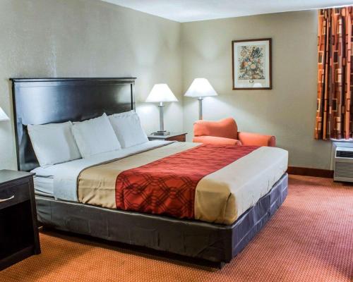 a hotel room with a bed and a chair at Econo Lodge Burlington I-40 in Burlington