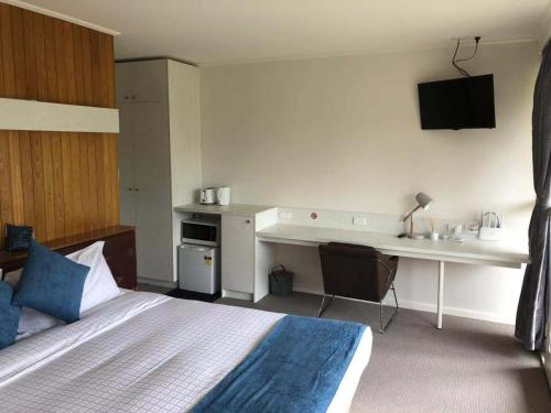 a hotel room with a bed and a desk with a sink at The Wurruk Motel in Sale