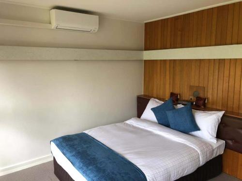 a bedroom with a bed with blue and white pillows at The Wurruk Motel in Sale
