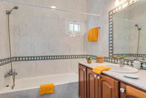 ein Badezimmer mit einer Badewanne, einem Waschbecken und einem Spiegel in der Unterkunft Villa Sol y Mar in Son Bou