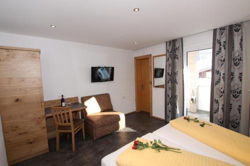 um quarto de hotel com duas camas e uma mesa e uma cadeira em Gästehaus Alpina em Sankt Anton am Arlberg