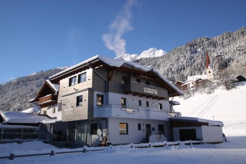 ein Gebäude mit Schnee auf dem Boden vor einem Berg in der Unterkunft Gästehaus Alpina in Sankt Anton am Arlberg