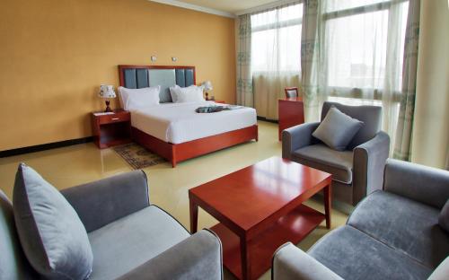 アディスアベバにあるHera Addis Hotelのベッド、椅子、テーブルが備わるホテルルームです。