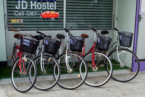 tre biciclette parcheggiate l'una accanto all'altra di fronte a un edificio di JD hostel a Phra Nakhon Si Ayutthaya