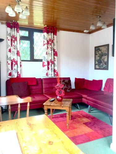 a living room with a red couch and a table at Tovey Lodge in Hassocks