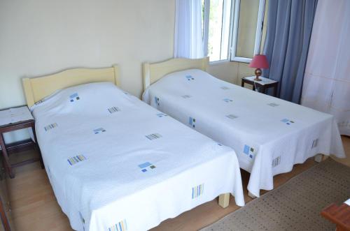 two beds in a hotel room with white sheets at Villa Radani in Trou dʼ Eau Douce