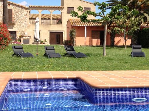 uma piscina com espreguiçadeiras num quintal em Can Mas em Sant Pere Pescador