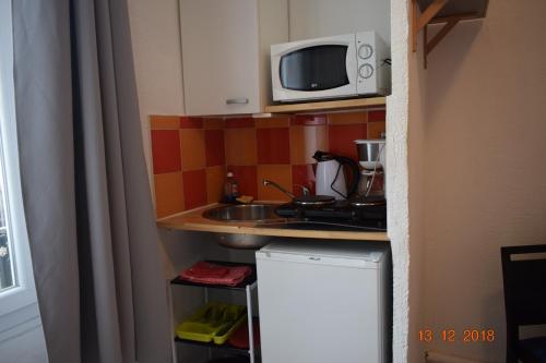a small kitchen with a sink and a microwave at Résidence Appartement Adonis in Nice