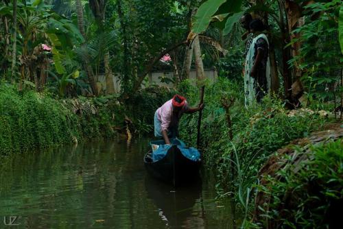a man is paddling a boat in a river at Munroe Meadows in Munroe Island