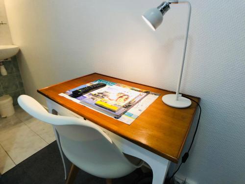 a desk with a lamp and a magazine on it at Cit'Hotel Le Volney in Saumur