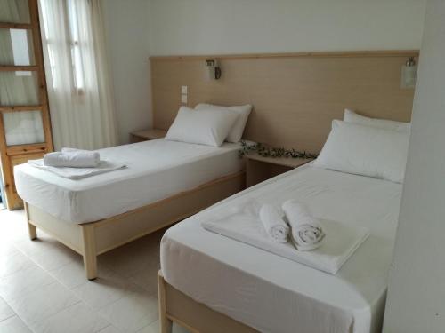 two beds in a room with towels on them at Zorbas Studios in Lefkos Karpathou