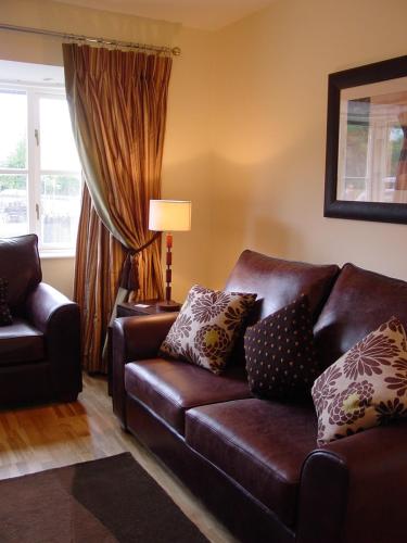 a living room with a brown leather couch and a window at ArdMullen Townhouse X Davitt's Guesthouse & Restaurant Kenmare in Kenmare