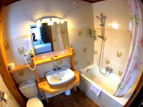 a bathroom with a sink and a toilet and a tub at Hotel Le Soly in Morzine