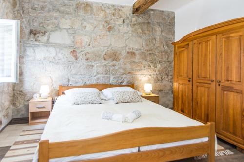 a bedroom with a large bed and a stone wall at Apartment Mileta Sali in Sali