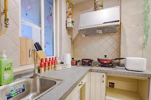 uma cozinha com um lavatório e um fogão forno superior em Chengdu Jinjiang·Taikoo Li· Locals Apartment 00177440 em Chengdu