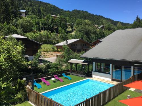 a swimming pool with chairs and a house at Hotel Le Soly in Morzine
