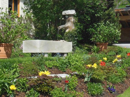 a garden with a fountain and flowers in a yard at Haus Schönleiten in Wagrain