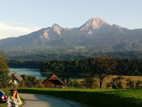 a woman walking down a road with mountains in the background at Kunterbunt Seehaus in Faak am See