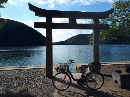 a bike parked in front of a toriiographical sign next to a lake at Midori Guesthouse&Hostel in Tsushima