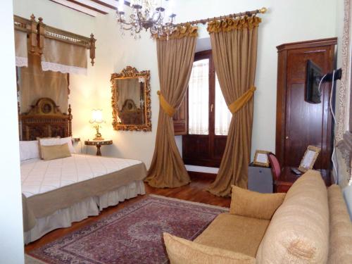 a bedroom with a bed and a couch at Hotel Boutique Nueve Leyendas in Úbeda