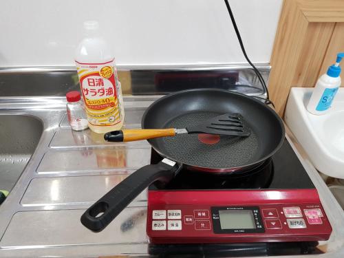 a pan on top of a stove with a spatula at Midori Guesthouse&Hostel in Tsushima