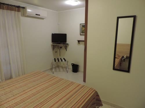 a bedroom with a bed and a mirror and a chair at Hotel Costa Balena-Piscina Aquecida Coberta in Guarujá