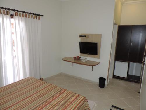 a bedroom with a bed and a tv on the wall at Hotel Costa Balena-Piscina Aquecida Coberta in Guarujá