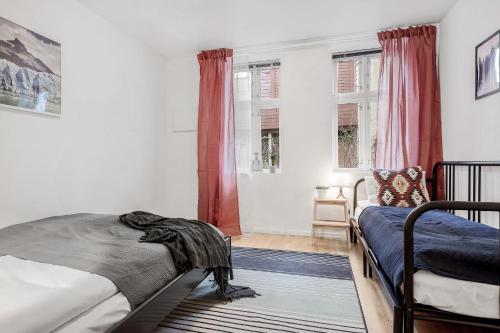 a bedroom with two beds and two windows at LS Apartments in Bergen