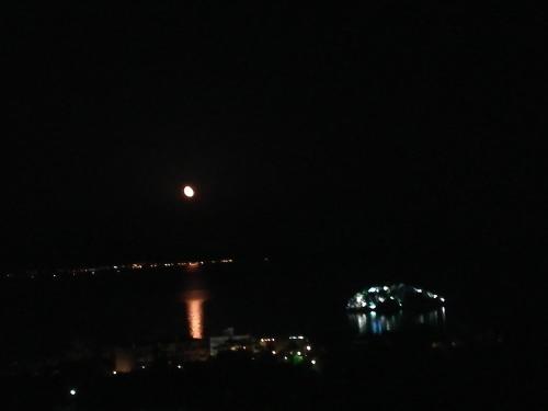 a moon over the water at night at Stone House in olive grove in Tolo