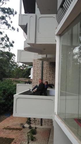 two people sitting on a balcony of a house at Panorama Green View Hotel Nuwara Eliya in Nuwara Eliya