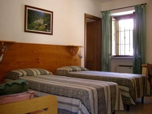 two beds in a hotel room with a window at L'Antico Borgo Rooms Rental in Caprie