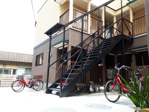 two bikes parked in front of a building with a staircase at Midori Guesthouse&Hostel in Tsushima