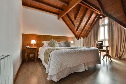 a bedroom with a large bed with a wooden ceiling at Micheline Hotel Tricot - ao lado da Rua Coberta in Gramado