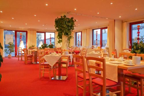 a dining room with tables and chairs and windows at Seehotel Weit Meer in Waren