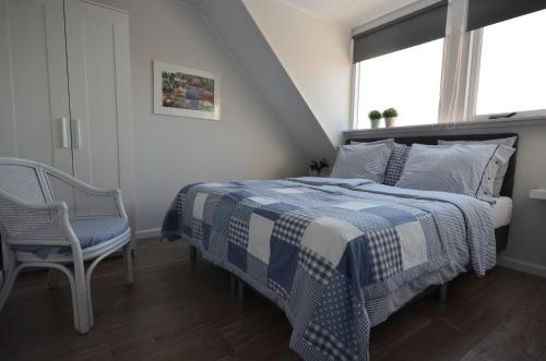 een slaapkamer met een blauw en wit bed en een stoel bij Zeevanlicht in Hollum